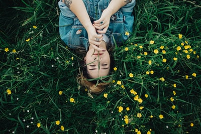 一个女人躺在草地上，开着黄色花瓣的花